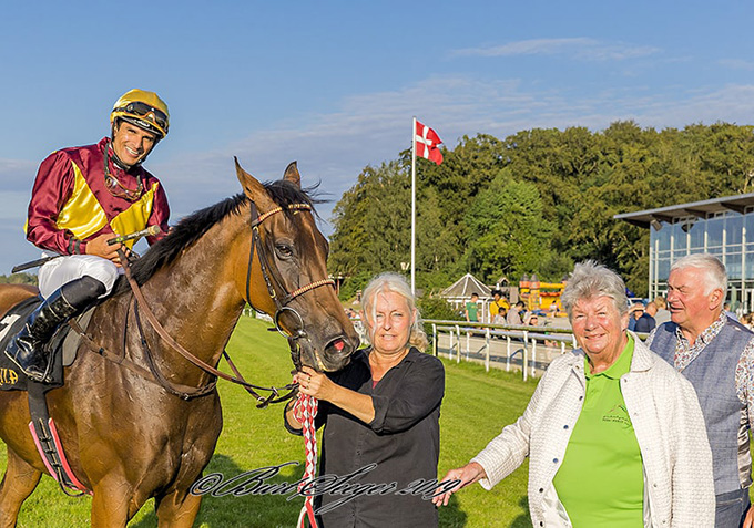 To uger efter Lone Kaj-Nielsens seneste sejr i 
	Svenskt Derby 2019 med Red Cactus (USA) indfinder Lone Kaj sig igen i vindercirklen, denne gang med Jubilance (IRE), redet af Elione Chaves, Klampenborg, lørdag den 27. juli, 2019. Foto Burt Seeger