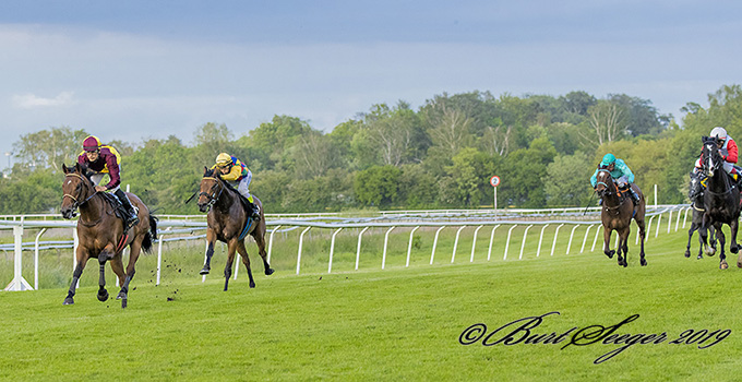 Talisman  med jockey Elione Chaves i front med mange længders føring, lørdag den 1. juni 2019, Klampenborg. Til højre i billedet ses Hongkong Honcho i Stald Klampenborgs rød hvide farver. Foto Burt Seeger