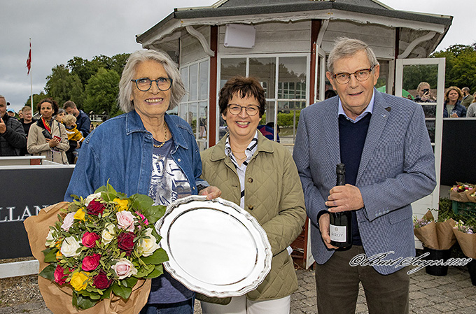 Lene Christiansen fra Christiansen Racing og  ejer af Happy Feet, med ærespræmie og blomster, i vindercirklen sammen med  Søren og Jette Hjorth fra Stutteri Hjortebo, der var sponsor for løbet. Foto Burt Seeger 