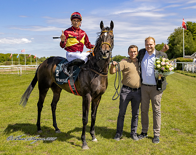Peter Keller repræsenterer Lone Kajs vinderhest Amicone (IRE), Klampenborg, lørdag den 20. maj 2023, mens Rasmus Olsen som beslagsmed kan tillade sig at tage en del af
	æren.  Foto Burt SeegerFoto Burt Seeger